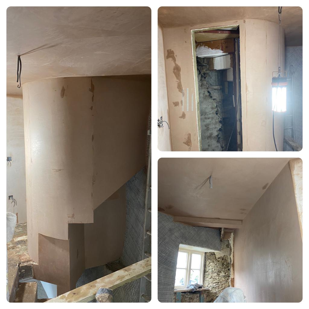 A curved plastered wall beside a staircase, and cottage rooms part way through the job