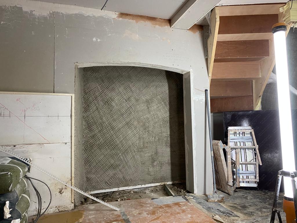 A recess beneath a staircase prepared with a scratch coat