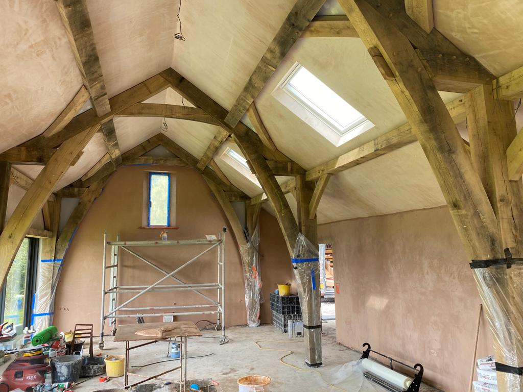 A vaulted oak-framed room with fresh plaster between the beams