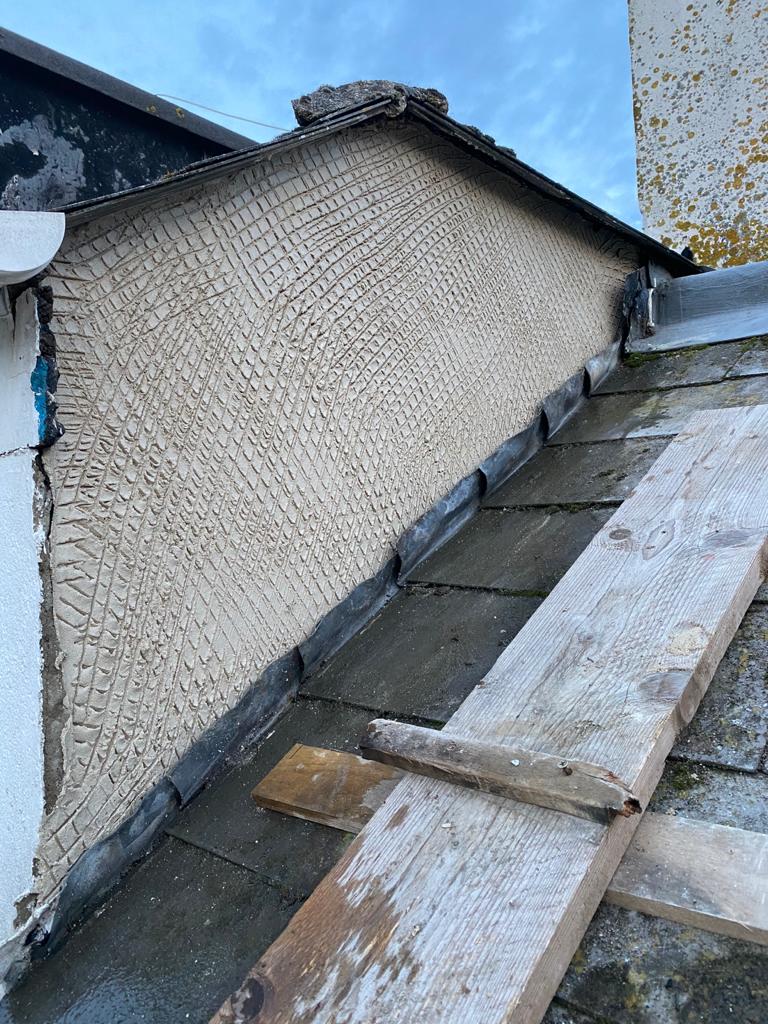 A gable end with a cross-hatched scratch coat, seen from the roof